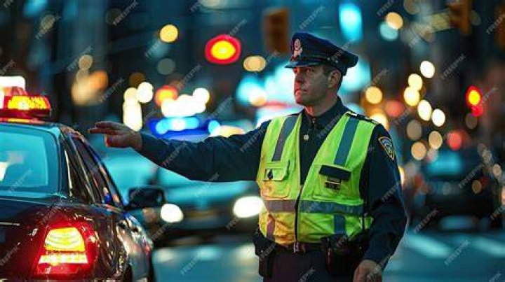 A traffic police officer making the stop sign and another riding a motorcycle in traffic