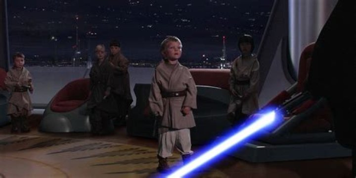 Anakin, with his lightsaber ignited, stands on rocks near a river of lava in Star Wars: Revenge of the Sith