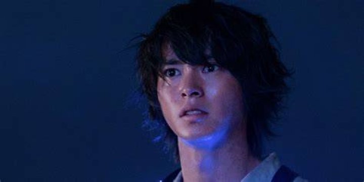 Arisu looking out, with a blue light on his face in Alice in Borderland.