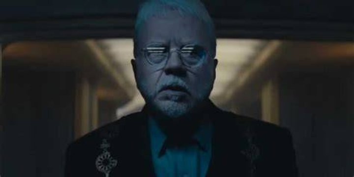 Bernard (Tim Robbins) looking in fear at the screen in his ceremonial outfit in Silo