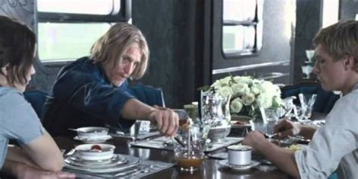 Haymitch eating breakfast with Katniss and Peeta on the train in The Hunger Games