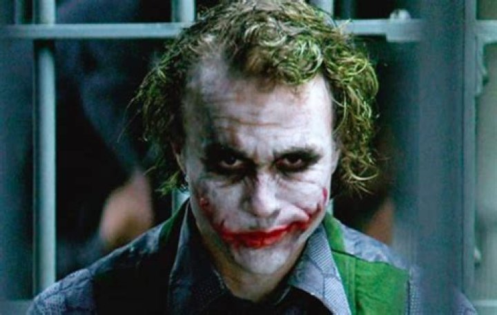 Heath Ledger as the Joker holding a playing card