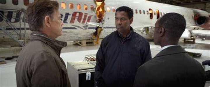 John Goodman and Denzel Washington sitting in a poorly-lit room in Fallen