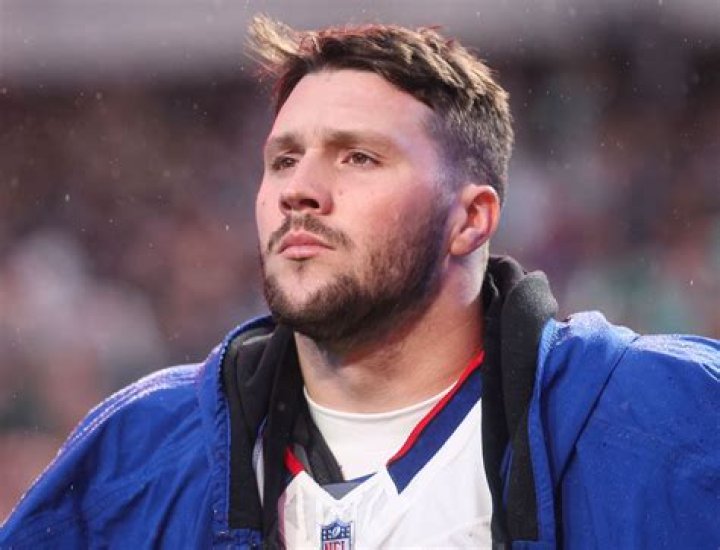 Josh Allen looking down with a football play happening in the background of Madden 24. 