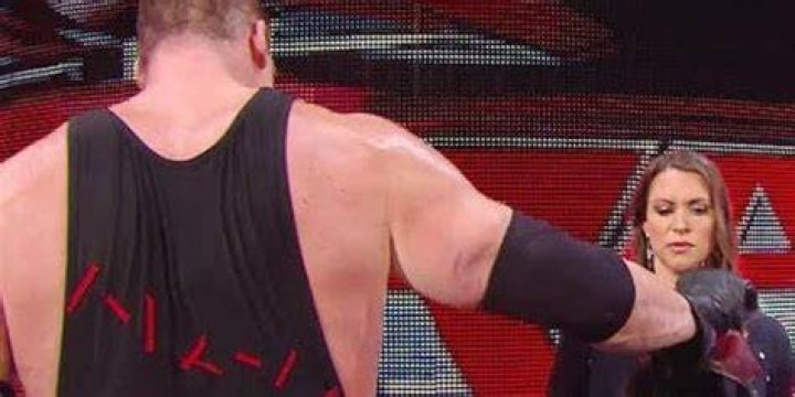 Kane handing his mask to Stephanie McMahon. 