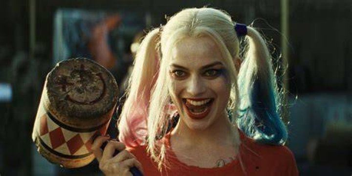 Margot Robbie as Harley Quinn in Birds of Prey against a pink and blue powder background.