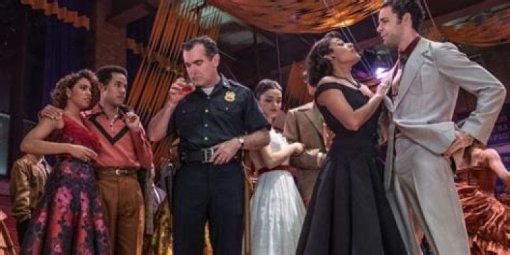 Officer Krupke smelling a drink while surrounded by Sharks in West Side Story 2021