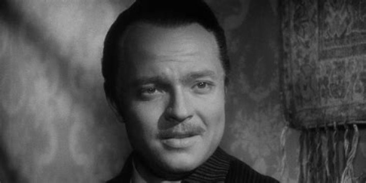 Orson Welles as Charles Foster Kane in Citizen Kane standing in front of a huge poster of himself