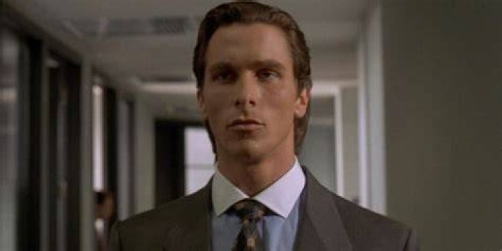 Patrick Bateman walking down the halls of his office lost in thought in American Pyscho