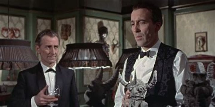 Peter Cushing glances at Christopher Lee in a living room in The Skull.