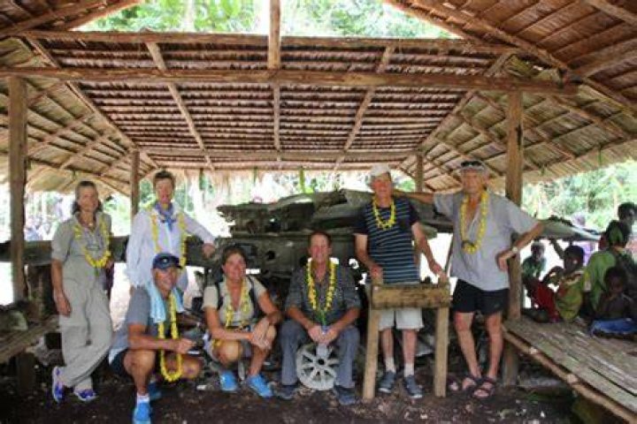 Phillida Eivers, Amanda Chrisp, David and Cate Williams, Hamish, Marcus and James Williams at the crash site.The plane debris is under an extended roof shelter built by locals. Photo / Supplied