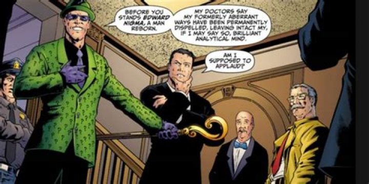 Riddler speaks to a crowd including Bruce Wayne