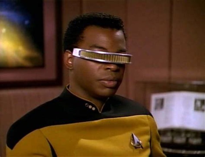 Star Trek man wearing black coat standing on rubbles with the USS Enterprise flying in background