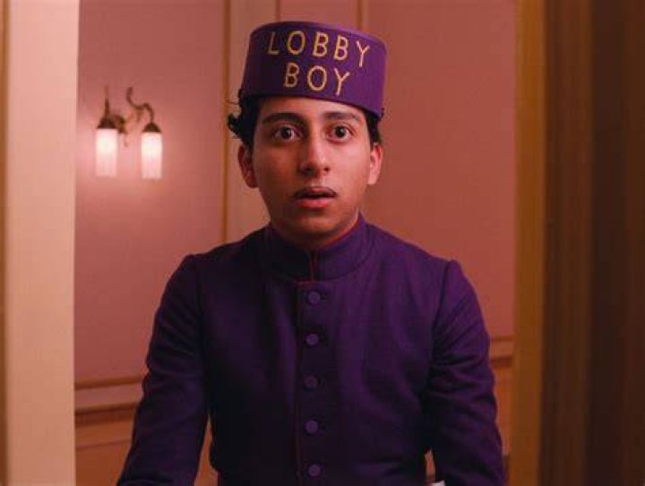 The Lobby Boy in purple on a train next to an image of Howl’s Moving Castle walking past a flock of sheep and a cottage