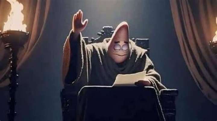 The Professor raising his hand and looking at a sheet of paper on a table in Money Heist Season 4.