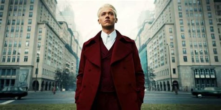 Tom Blyth as Coryo Snow wearing red coat and standing in street in The Hunger Games The Ballad of Songbirds and Snakes (1)