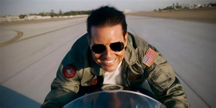 Tom Cruise smiling while riding a motorcycle in Top Gun: Maverick